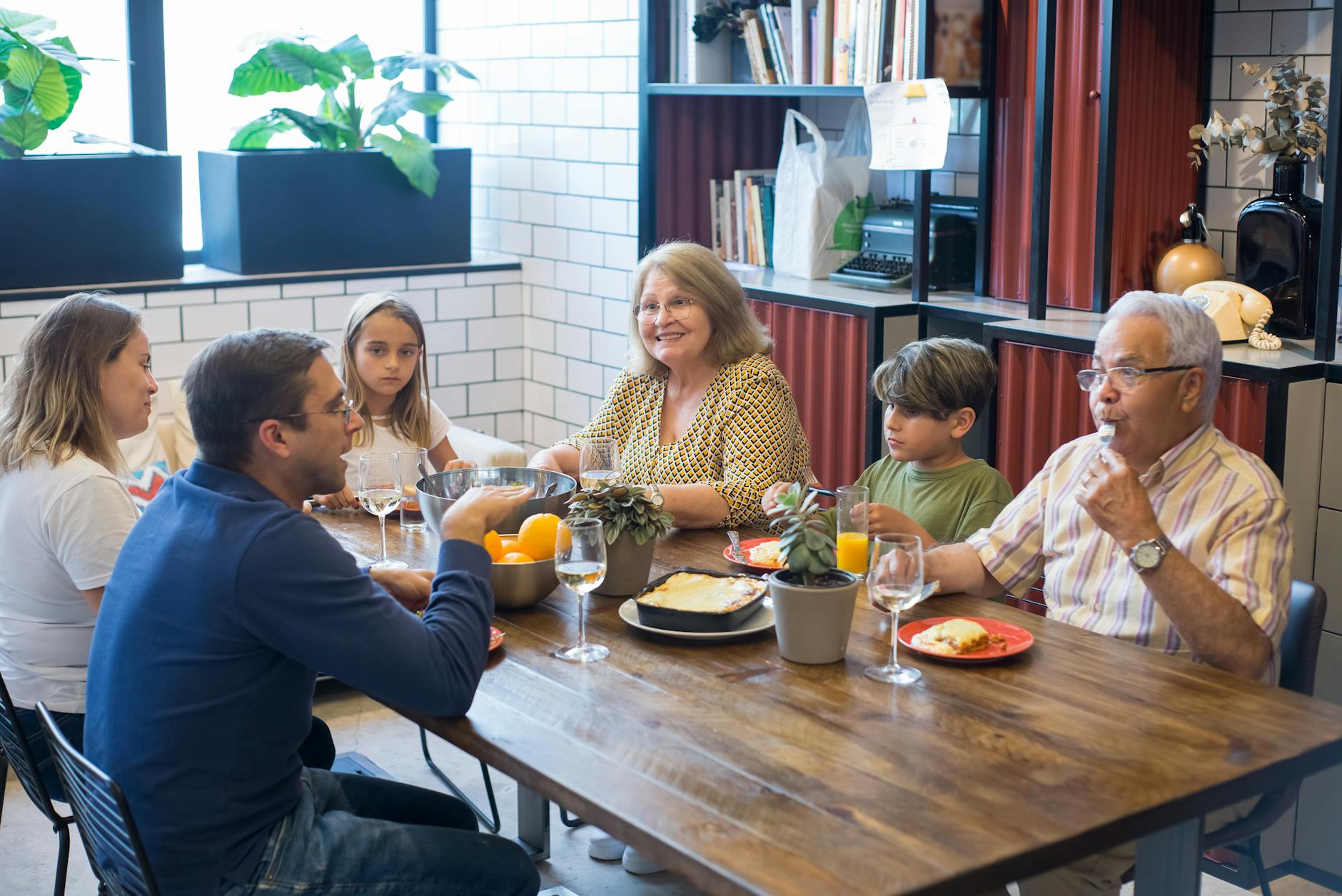 grandparents parents and kids having dinner at wooden table